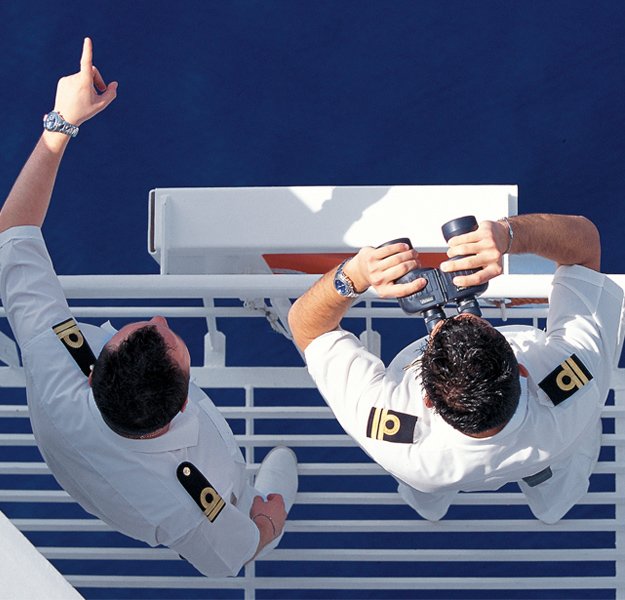 Two cruise ship officers observing the ocean and using binoculars | MSC Cruises Two cruise ship officers observing the ocean and using binoculars | MSC Cruises