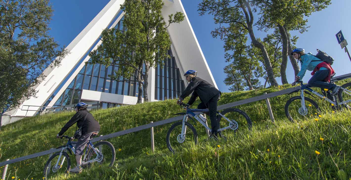 Cyclists riding past the Arctic Cathedral in Tromsø, Norway | MSC Cruises