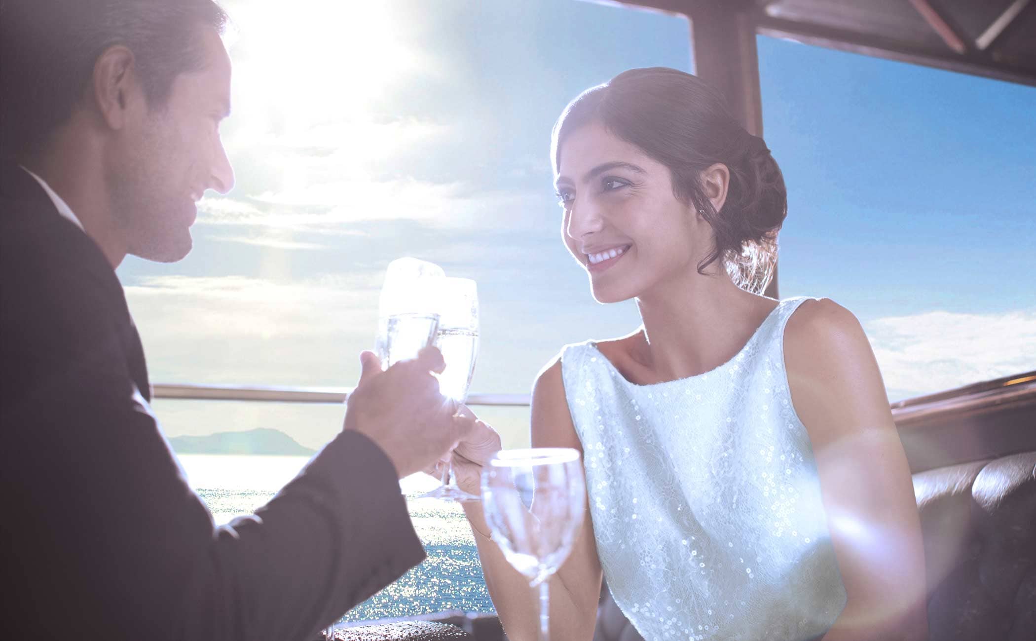 A couple toasting with glasses of sparkling water on a cruise deck under a sunny sky | MSC Cruises