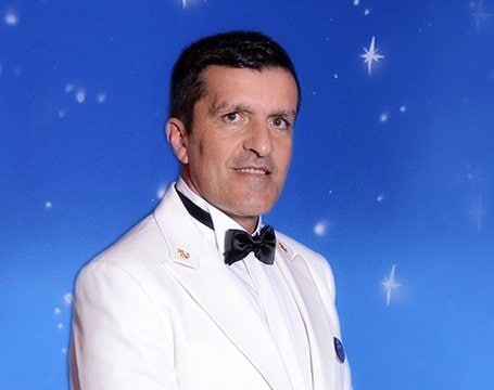 A formal attire crew member against a starry blue background | MSC Cruises A formal attire crew member against a starry blue background | MSC Cruises